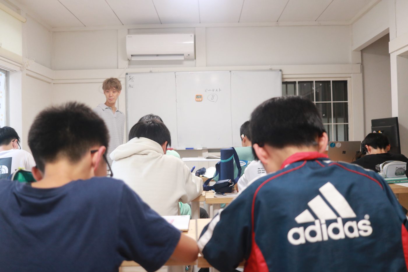 板書の前に立つ代表の石井と、それを見る子どもたちの後ろ姿