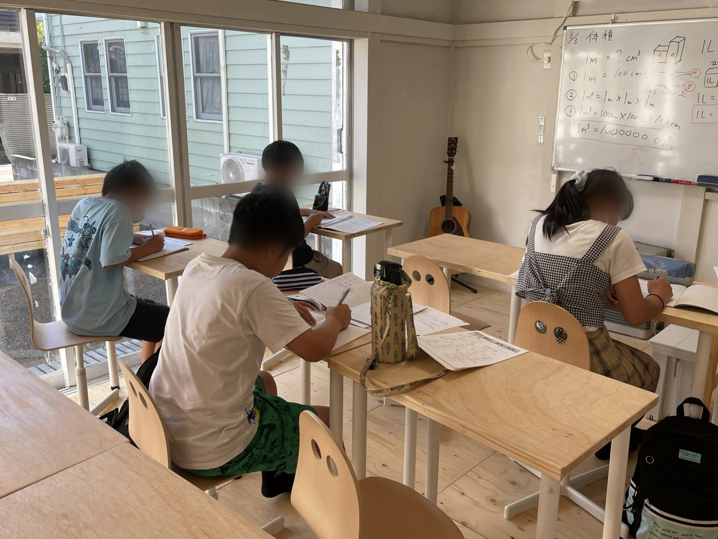 教室で机に向かい、テストの用紙に書き込んでいる子どもたち